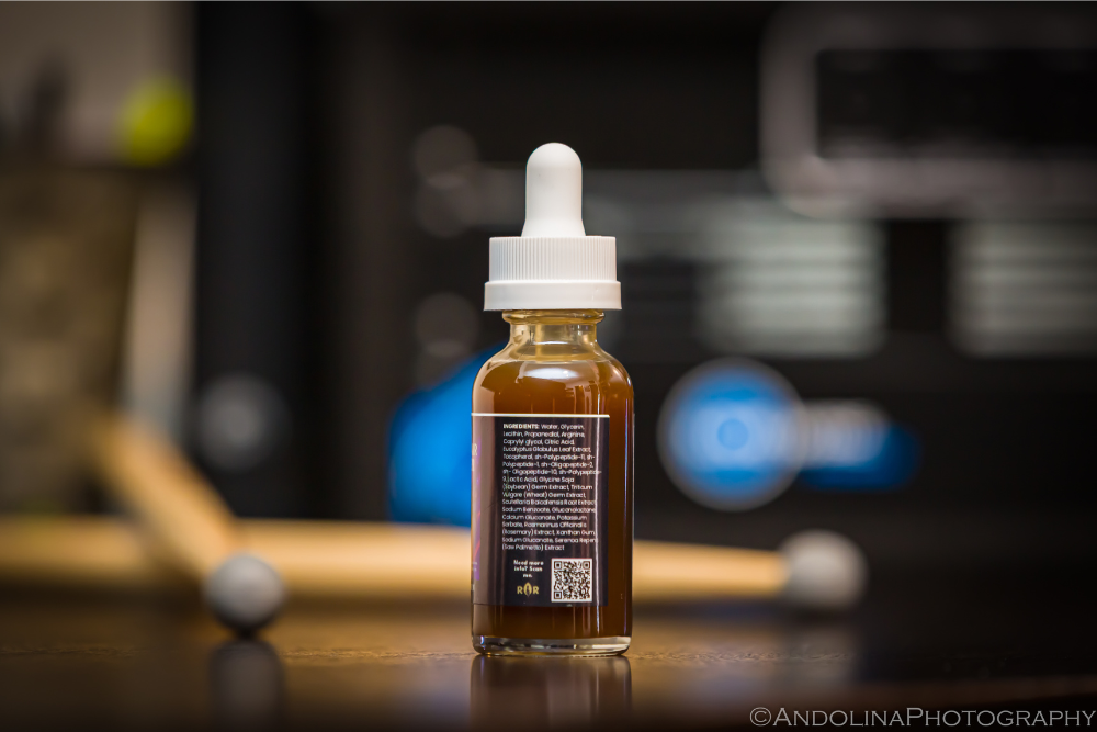Peptide hair amplifier on a desk with drumsticks and interface in the background