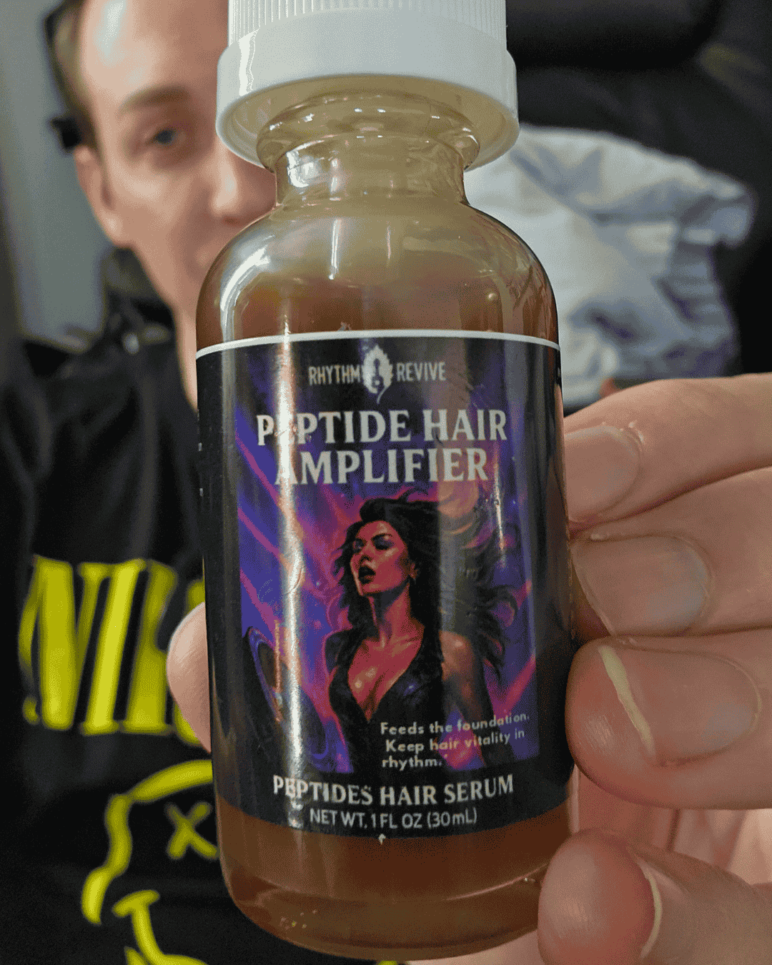 Bottle of Rhythm Revive Peptide Hair Amplifier held by a person.